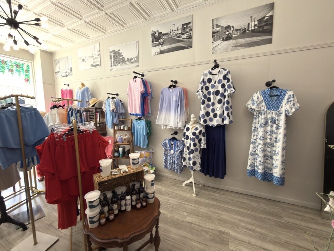 Boutique interior with blue and white clothing displayed under historic Piedmont photographs