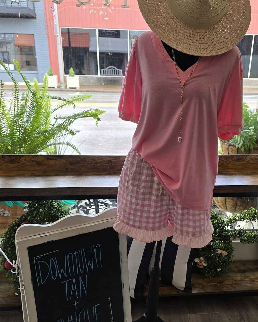 Pink v-neck top with pink gingham ruffle shorts and straw hat on a mannequin
